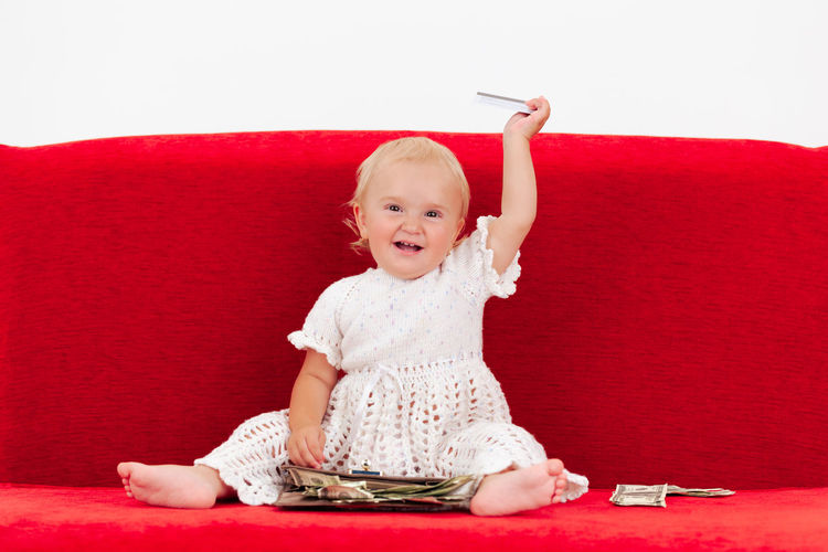 Cute baby girl sitting on red couch