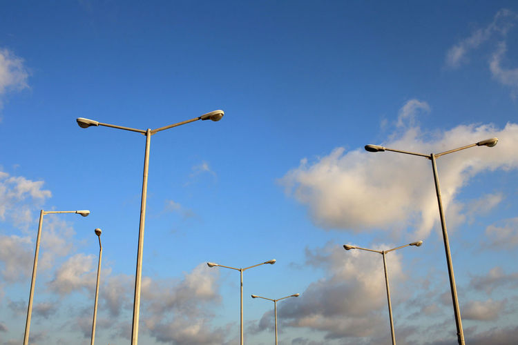 Low angle view of street lights against blue sky