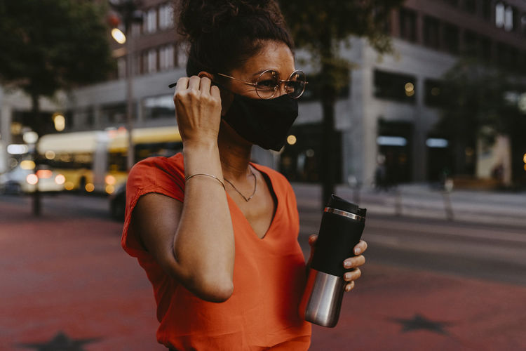 Businesswoman with protective face mask and insulated container in city