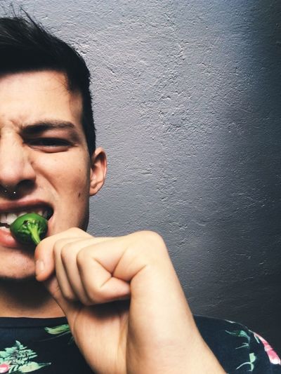 Close-up of young man eating chili pepper
