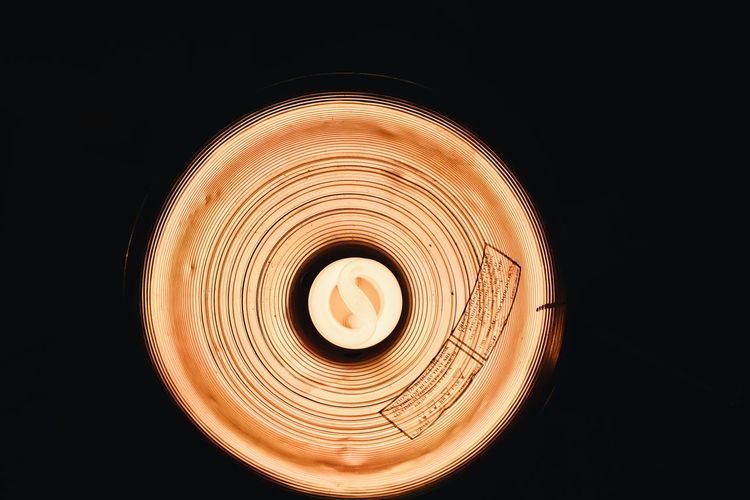 Directly below view of illuminated light bulb against black background