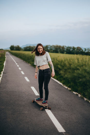 Portrait of young woman skateboarding on road