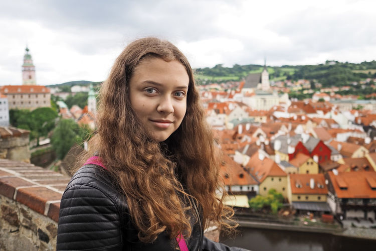 Young girl takes a selfie photo on the background of the historic town, city czech krumlov,