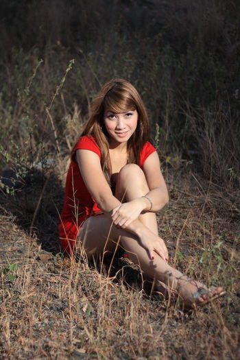 Portrait of smiling young woman sitting on land