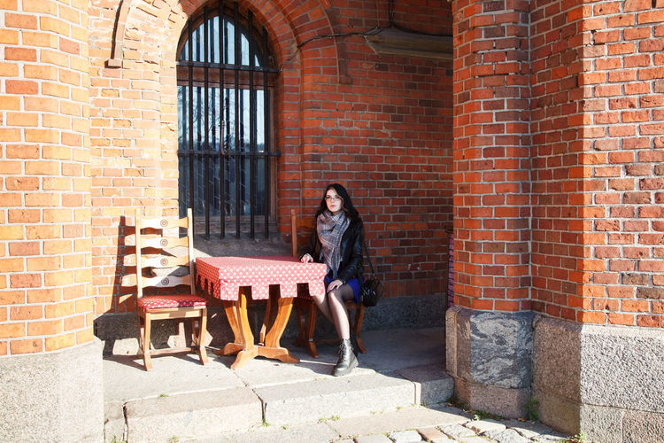 Rear view of woman sitting against wall