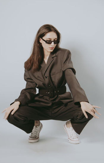 Young woman sitting against white background