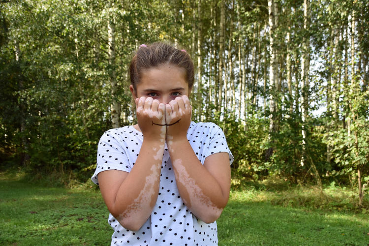Portrait of smiling girl standing against trees