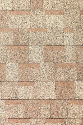 Background and texture of rectangular tiles of beige color of roofing bituminous tiles.