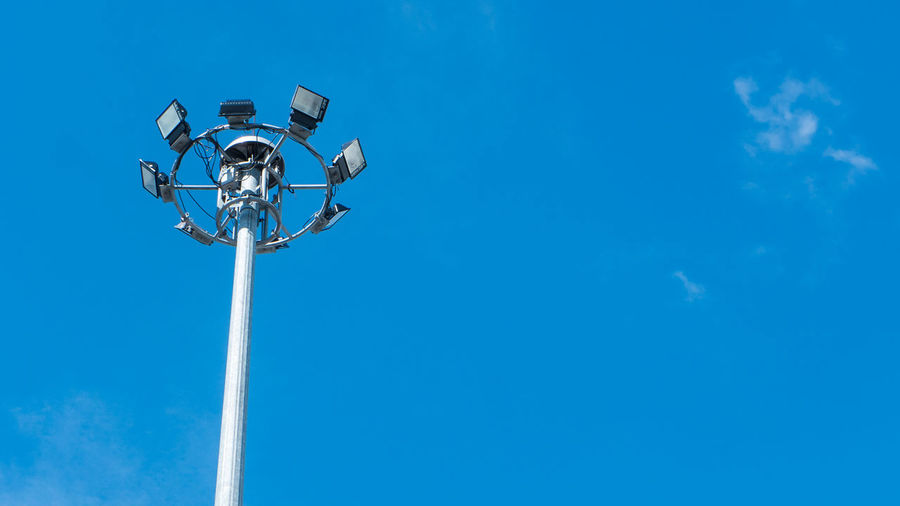 Low angle view of floodlights against clear blue sky
