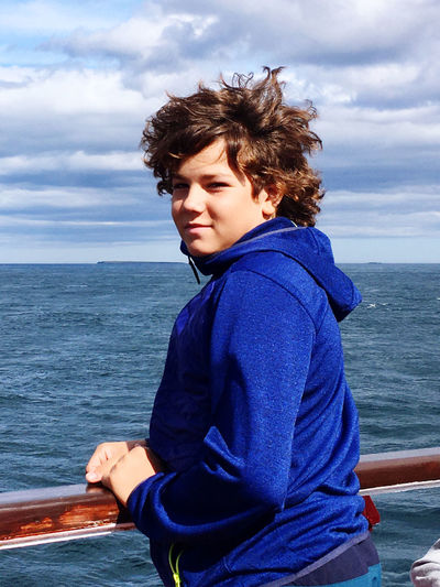 Portrait of teenager looking at sea against sky