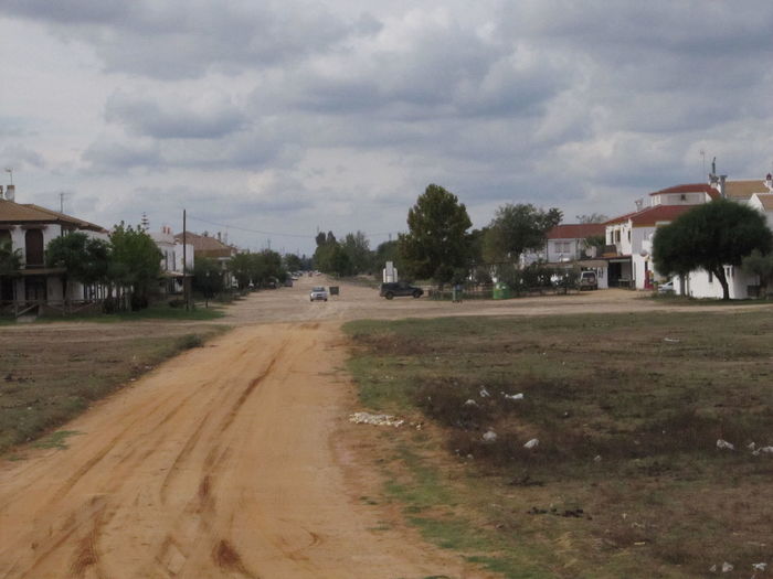 View of road and buildings against cloudy sky