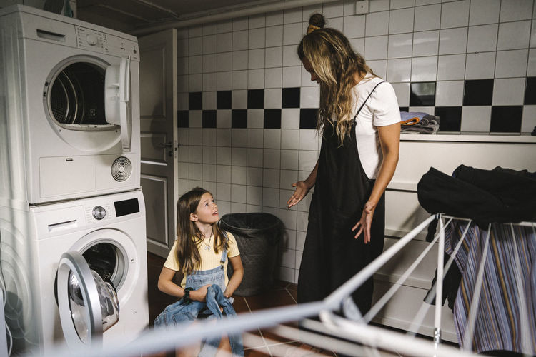 Mother and daughter doing laundry in utility room