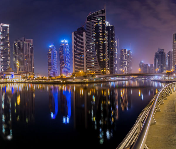Night city dubai in uae. illuminated buildings by river against sky in city at night