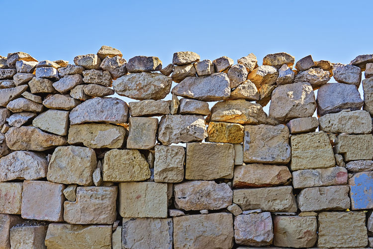 Low angle view of stone wall against blue sky