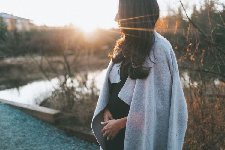 Pregnant woman standing at park during sunset