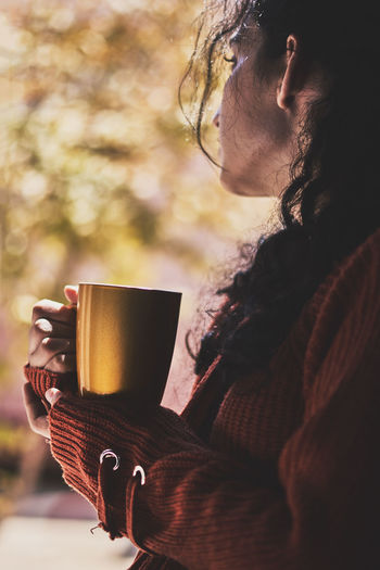 Cold autumn days - a young multi-racial female drinks coffee in a cozy windowsill. middle-eastern or