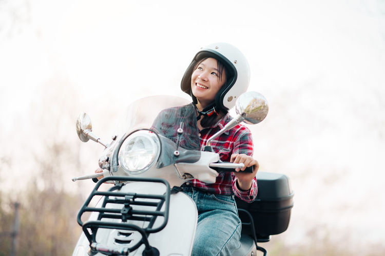 Portrait of smiling young woman riding motorcycle on road