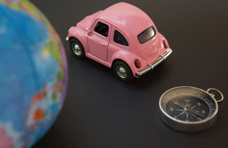 Close-up of toy car and navigational compass on black background