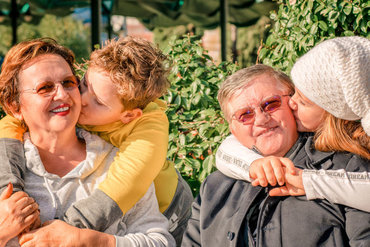 Happy kids hugging and kissing their grandparents 