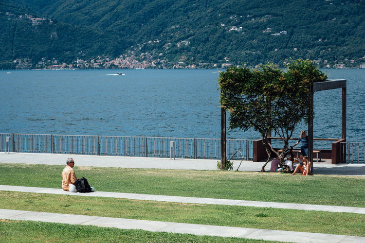People sitting at park by sea