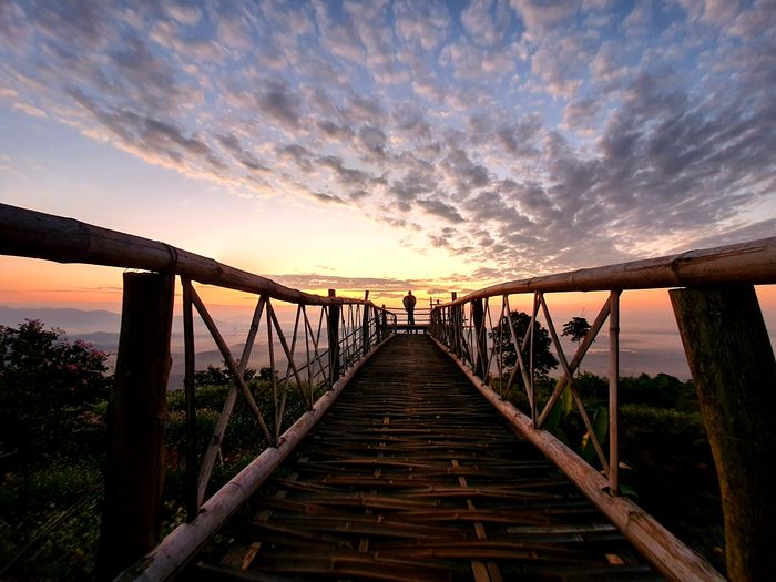 Footbridge over bridge against sky during sunset