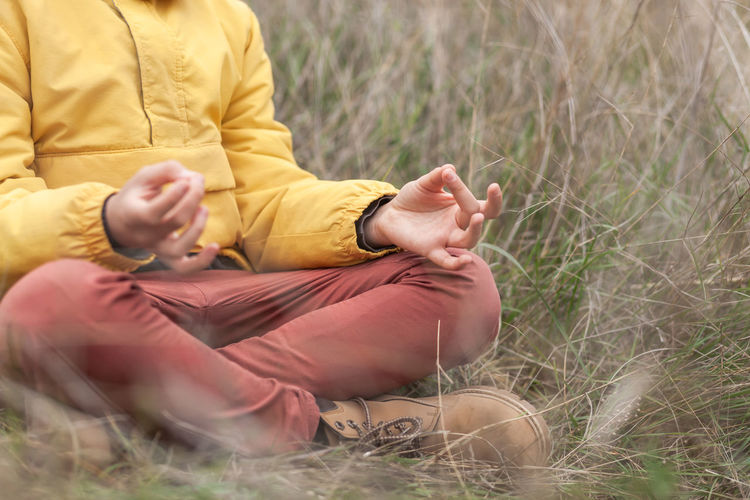 Low section of person meditating at field