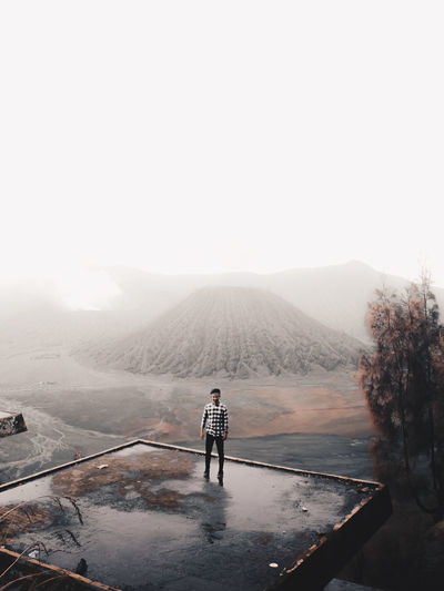 Full length of man standing against mountains and sky during foggy weather