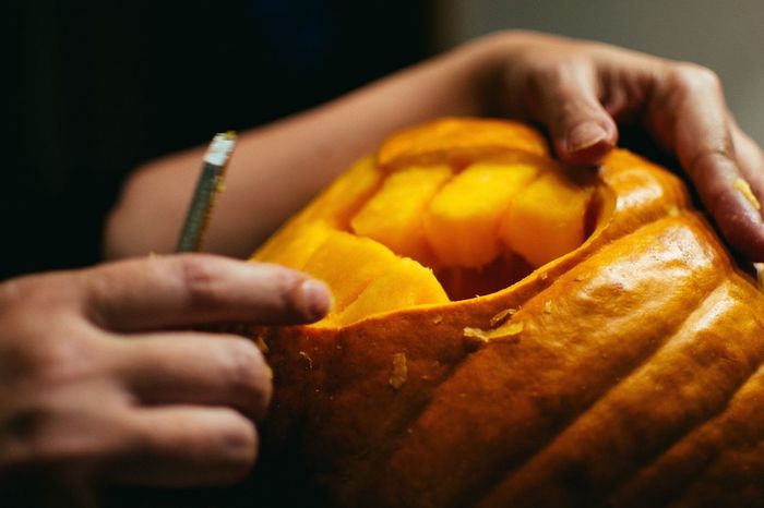 Cropped image of boy carving pumpkin for halloween