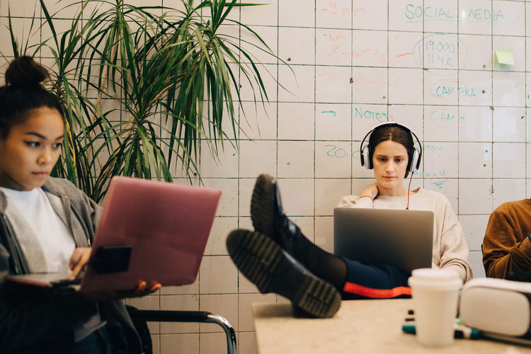 Young multi-ethnic female computer programmers using laptops at small creative office