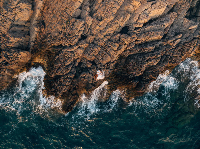 Aerial view of couple lying on rock by sea