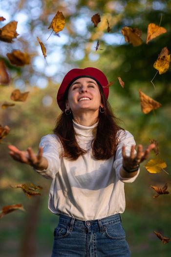 Smiling young woman standing against plants during autumn