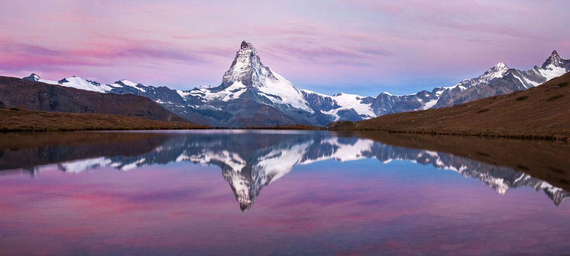 Scenic view of lake and snowcapped mountains against sky during sunset