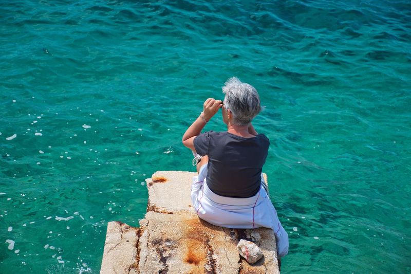 High angle portrait of senior woman sitting on the sea shore