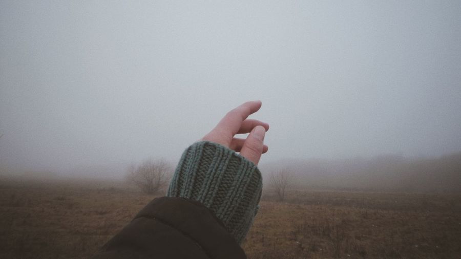 Midsection of person on field against sky during foggy weather
