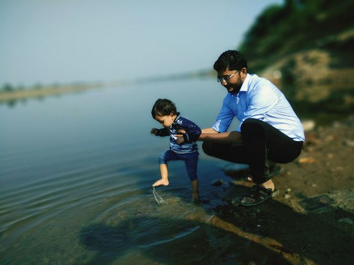 Father and holding son playing at riverbank