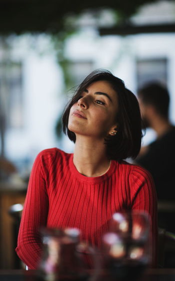 Young woman looking away while sitting indoors