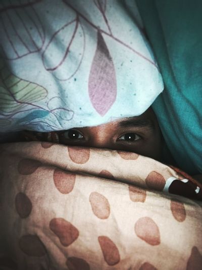Portrait of person peeking though blankets