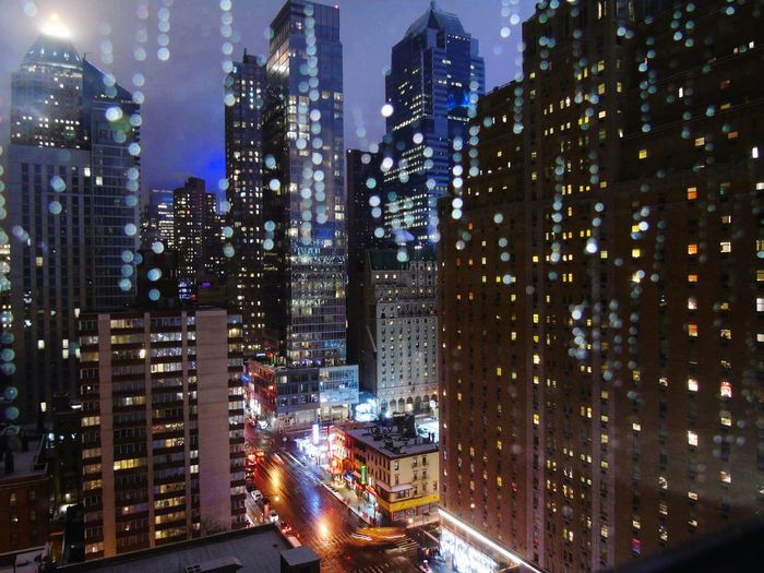 Illuminated modern buildings in city see through glass window at night