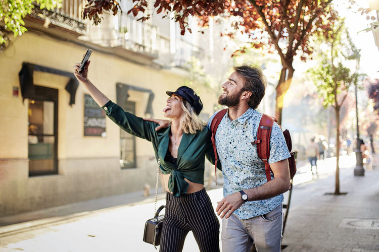 Cheerful couple doing selfie while standing outdoors