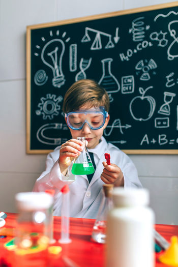 Cute boy examining chemical in classroom