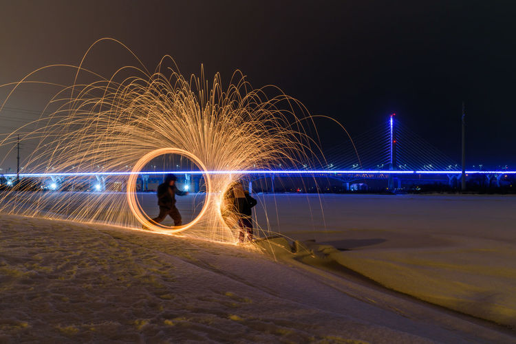 Illuminated wire wool on sand against sky at night