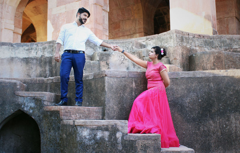 Couple posing for a romantic hand-holding shot with anancient fort backdrop