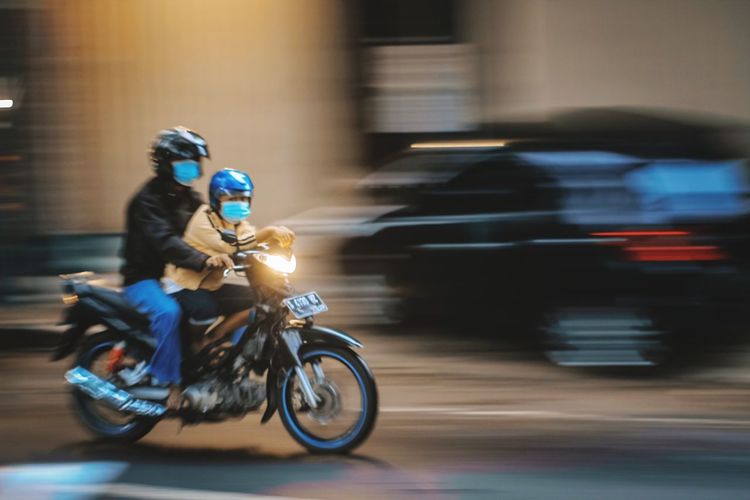 Blurred motion of man riding motorcycle on road