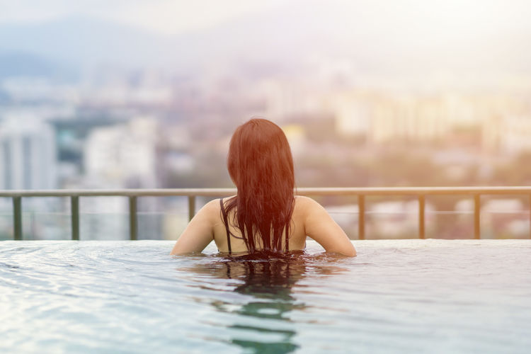 Rear view of woman sitting in swimming pool