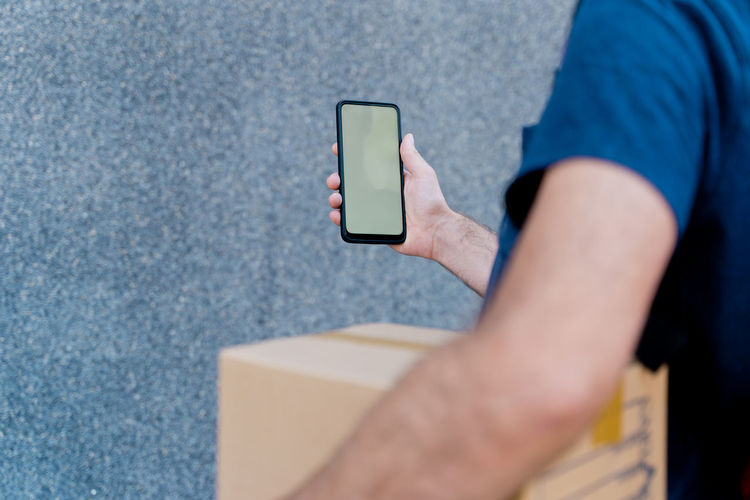 Midsection of delivery person using mobile phone outdoors