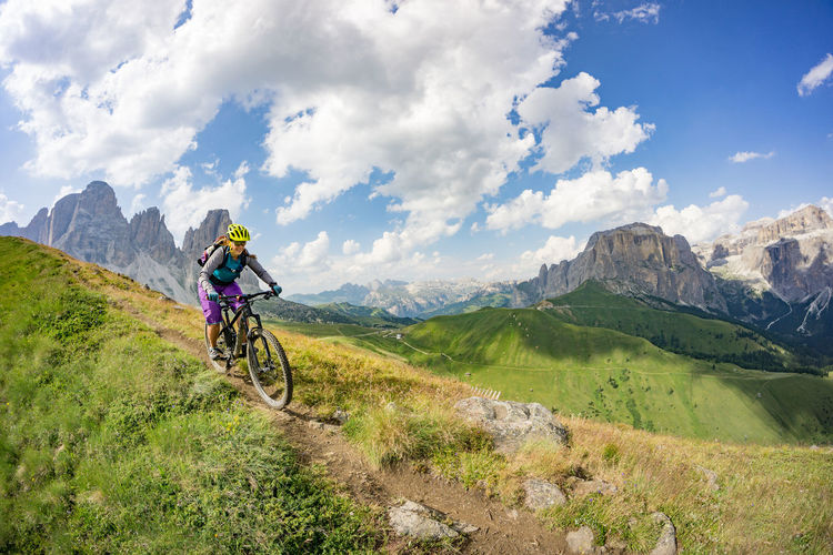 Woman riding a mountain bike on footpath in the dolomites, italy