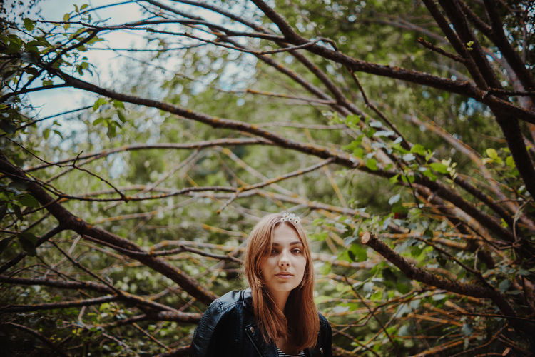 Portrait of young woman against trees
