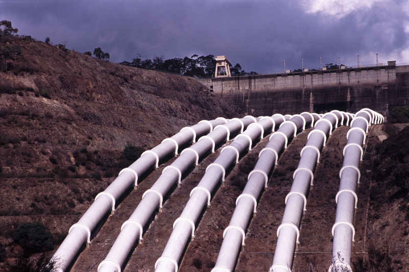 Pipelines on mountain against cloudy sky