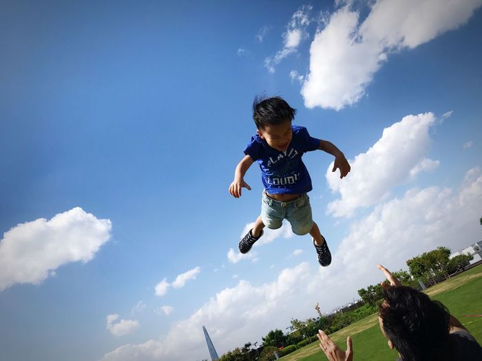 Rear view of father throwing son in mid-air at park