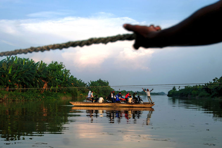 People in boat on river against sky